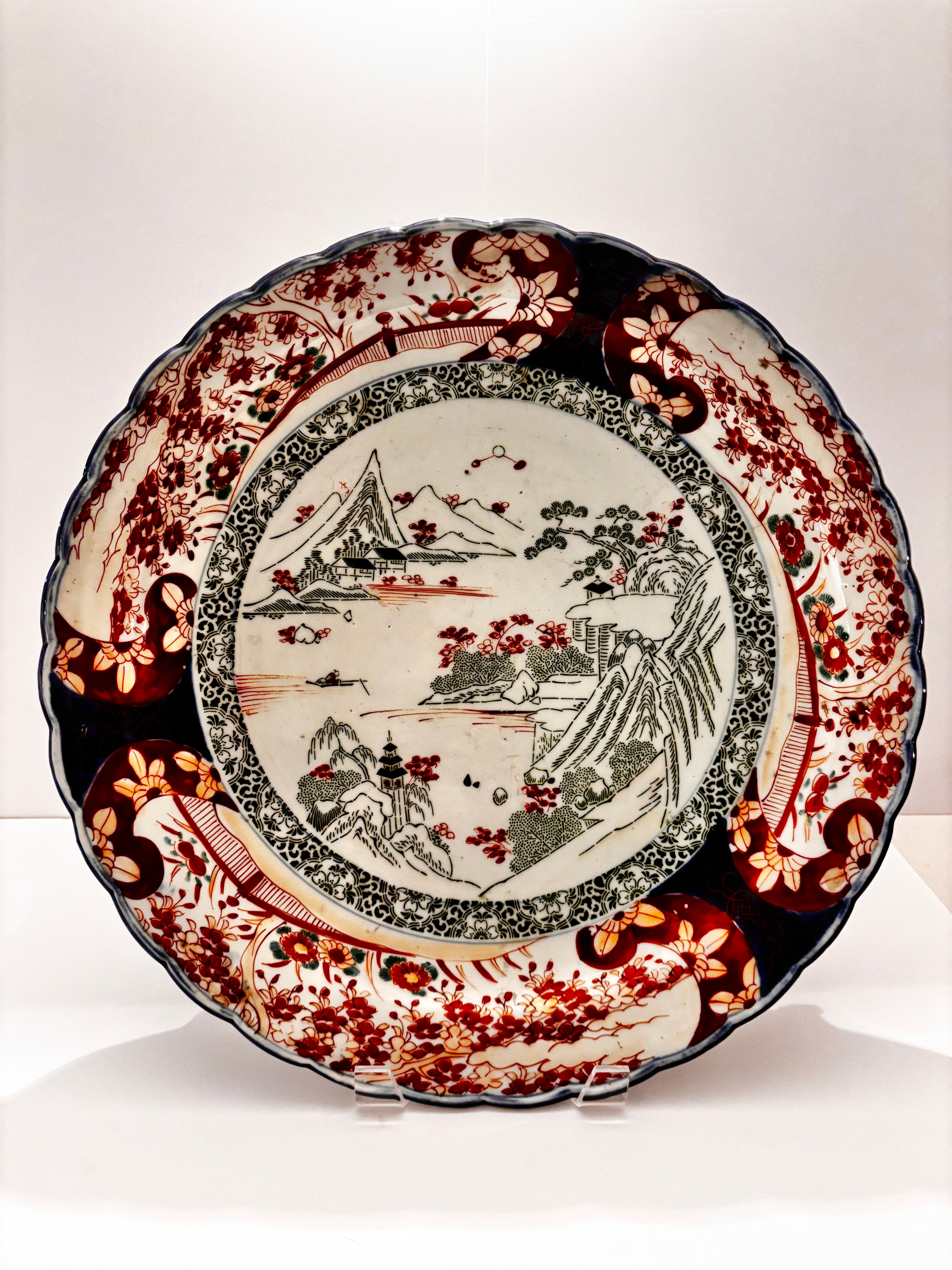 Imari porcelain charger from 1940s Japan with a landscape center and red, blue, and gold border