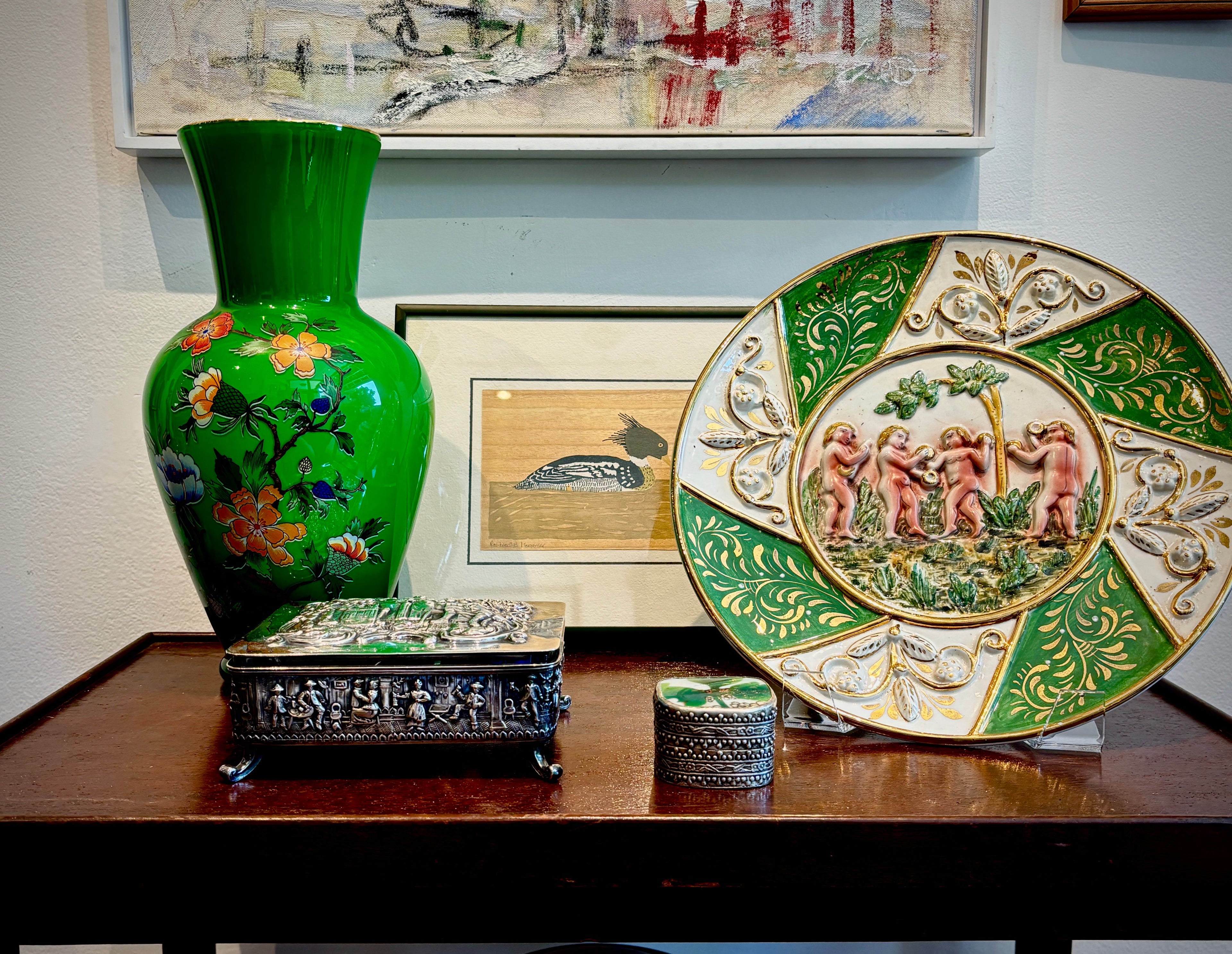 A green-themed setting with case, decorative dish, duck print and a silver box