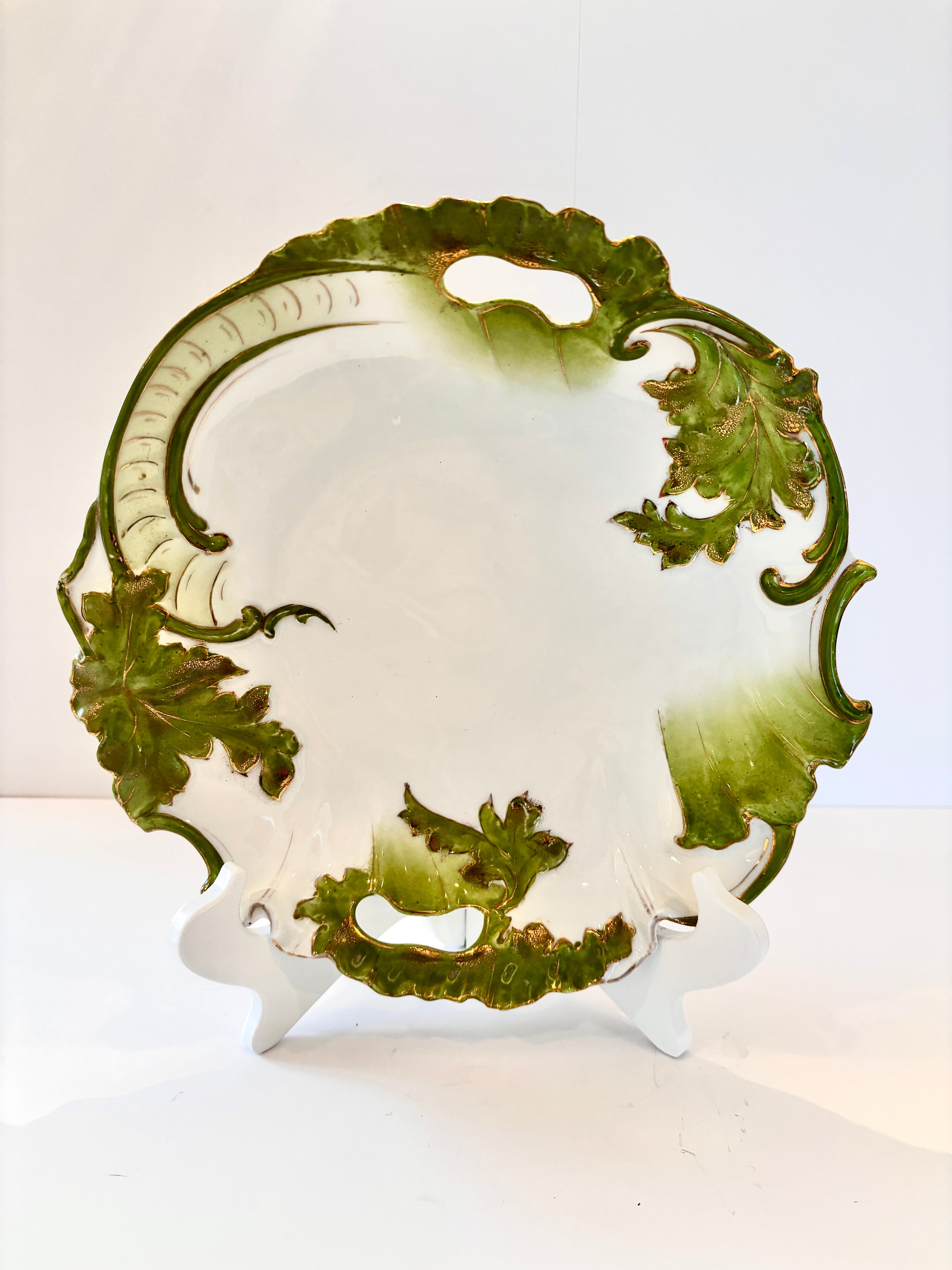 Vintage porcelain plate with green and gold painted leaves, scalloped edge and handles
