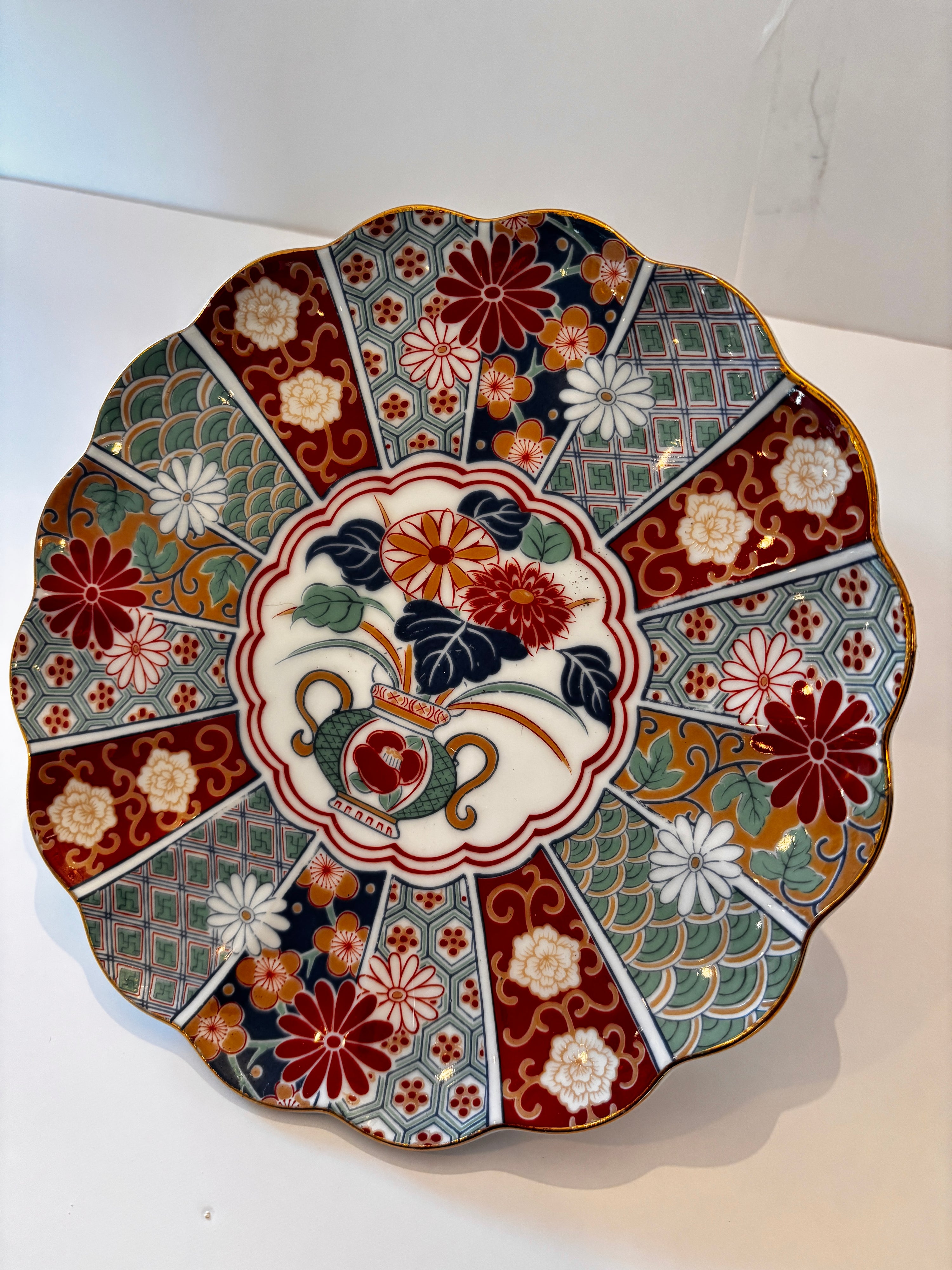 Vintage Japanese Imari plate with a teapot and chrysanthemum center and radiating panels in red, navy, green, and gold