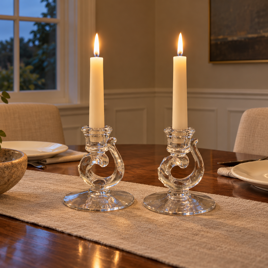 Pair of Fostoria clear glass scroll candleholders with ivory tapers on a walnut dining table