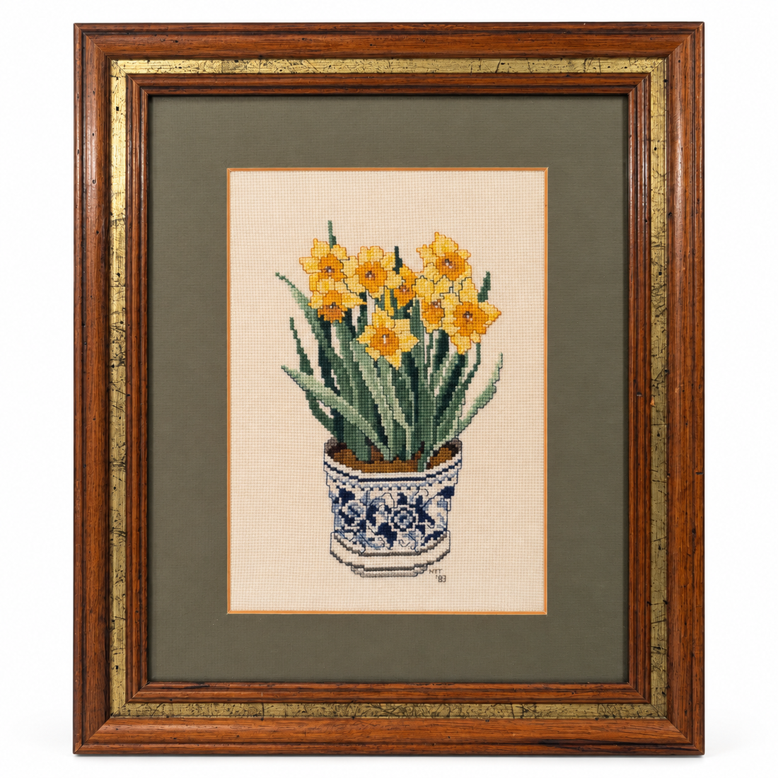 Vintage cross-stitch of daffodils in a blue and white pot, sage mat, wood and gold frame