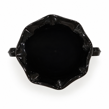 Looking down into a black amethyst glass trophy vase with ruffled rim, on white background