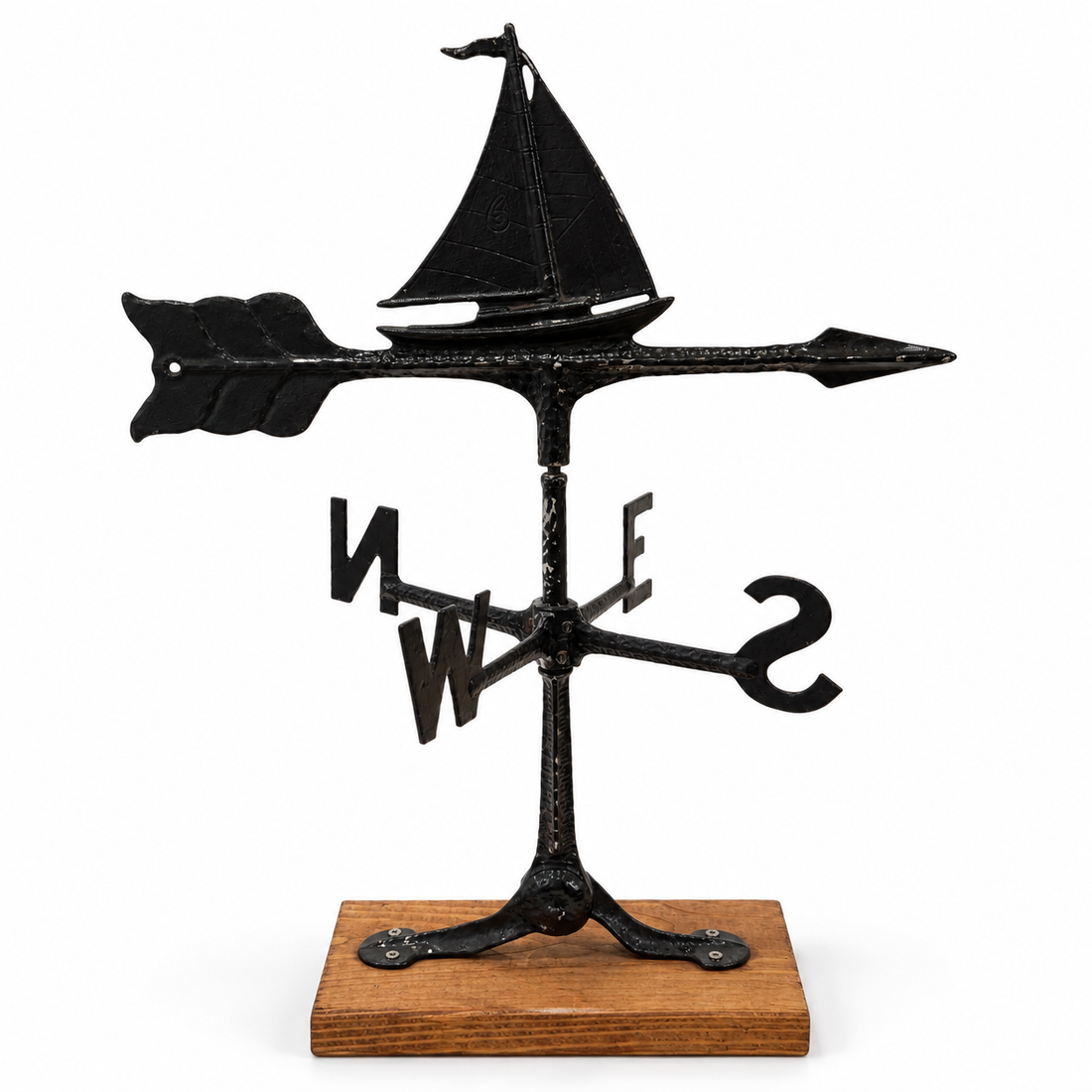 Cast metal sailboat weathervane with compass letters on wood base, front view